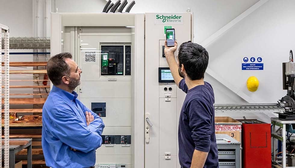 Two technicians interacting with a Schneider Electric smart panel in a modern industrial setting